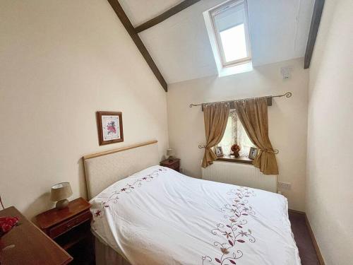 a bedroom with a white bed and a window at STONE BUILT BARN in a beautiful RURAL setting in Llangwm-isaf