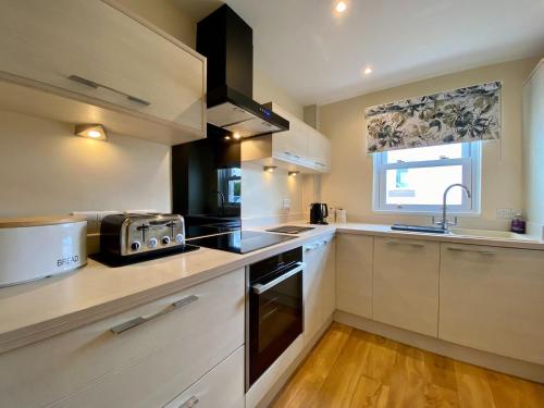 a kitchen with white cabinets and a sink and a microwave at 8 Howrahs Court, Keswick in Keswick