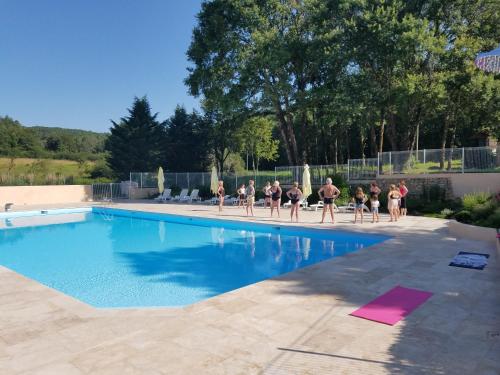 Un groupe de personnes fait du yoga au bord de la piscine. dans l'établissement Chalets et mobilhomes les Tourterelles, à Tourtoirac