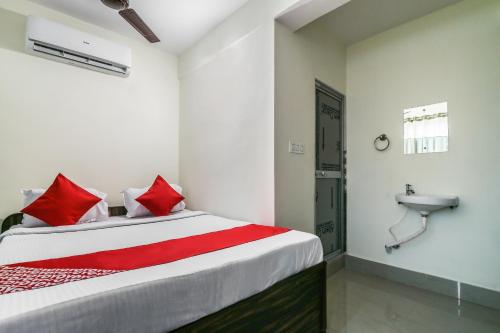 a bedroom with a bed with red pillows and a sink at OYO Flagship Hotel Lokenath in Jamshedpur