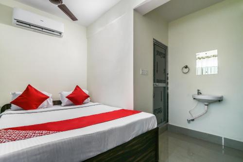 a bedroom with a bed with red pillows and a sink at Hotel O Lokenath in Jamshedpur