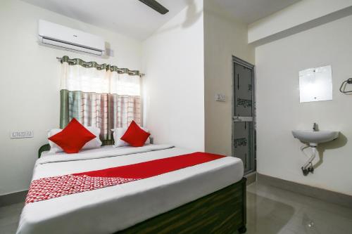 1 dormitorio con cama con almohadas rojas y lavamanos en OYO Flagship Hotel Lokenath en Jamshedpur