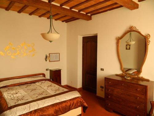 ein Schlafzimmer mit einem Bett und einem Spiegel auf einer Kommode in der Unterkunft Palazzo Nanni in Montefalco