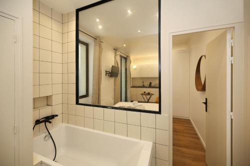 a bathroom with a white tub and a mirror at Studio fonctionnel tout équipé proche métro - 2P in Paris