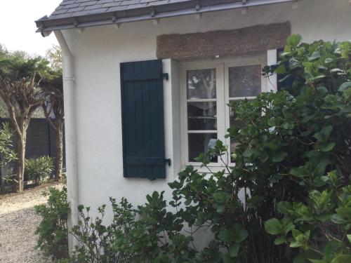 a window with a green shutter on a white house at Charmant duplex in La Baule