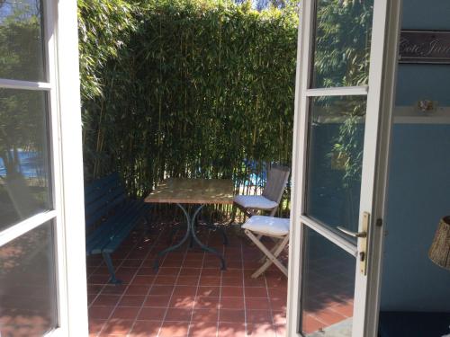Une porte ouverte s'ouvre sur une terrasse avec une table et un banc. dans l'établissement Charmant duplex, à La Baule
