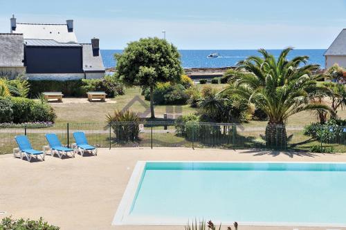 uma piscina com duas cadeiras azuis e o oceano em LocaLise au Guilvinec - A16 - Vue sur la mer, la piscine et le jardin - Tout à pied, plages, port, centre, commerces, marché - Wifi inclus - Animaux bienvenus - Linge de lit inclus em Le Guilvinec