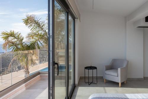 a living room with glass doors and a chair at Saronida Hills in Saronida