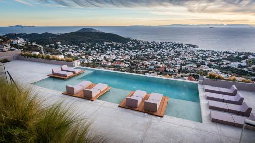 a swimming pool with lounge chairs and a view of the city at Saronida Hills in Saronida