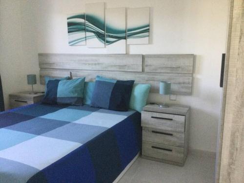 a bedroom with a blue and white bed and a nightstand at Natural y sano: Charco del Palo in Charco del Palo