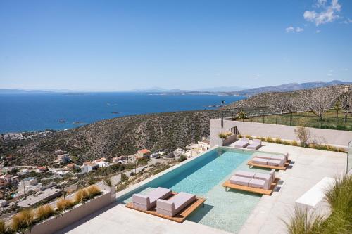 a swimming pool with lounge chairs and the ocean at Saronida Hills in Saronida