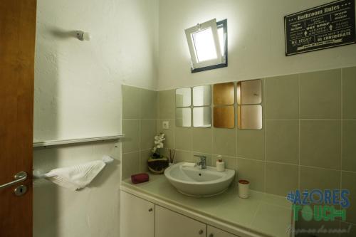 y baño con lavabo y espejo. en Casa do Merendário, en Praia da Vitória
