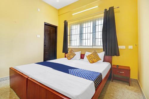 um quarto com uma cama com paredes amarelas e uma janela em SPOT ON Kayal Residency em Coimbatore