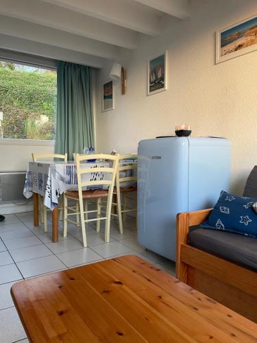 un salon avec une table et un réfrigérateur dans l'établissement Maisonnette, Résidence les gîtes de Trestel, à Trévou-Tréguignec