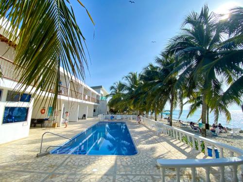 einen Pool neben einem Strand mit Palmen in der Unterkunft Hotel Costa Linda in Tolú
