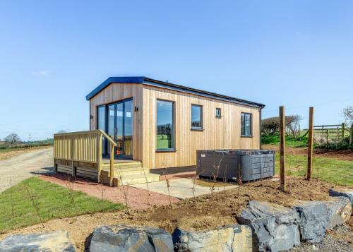 a small wooden house with glass windows on a field at Belan View Lodges in Welshpool