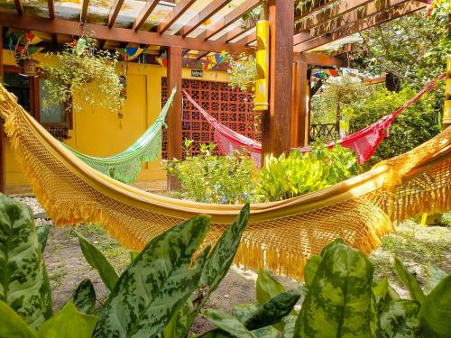 a hammock in front of a building with plants at Paranambuca Pousada in Porto De Galinhas