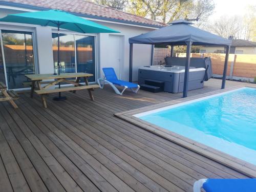 - une terrasse avec une table et un parasol à côté de la piscine dans l'établissement Magnifique Villa sur le Bassin d'Arcachon - JACUZZI+PISCINE - 8à10pers, à Biganos