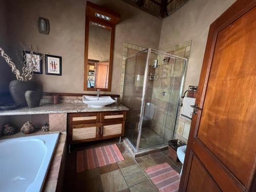 a bathroom with a shower and a sink and a tub at Pumula Bush Chalet in Mabula