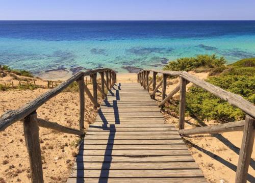 una passerella di legno che conduce alla spiaggia vicino all'oceano di La Domaggera a Maruggio