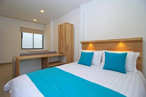 a bedroom with a large bed with blue and white pillows at Apart Hotel Casa Blanca in Cuenca