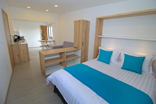 a bedroom with a blue and white bed and a desk at Apart Hotel Casa Blanca in Cuenca