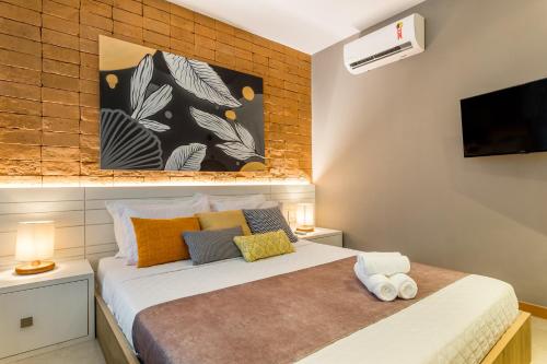 1 dormitorio con 1 cama y TV en la pared en Bravo Pousada Design, en Cabo Frío