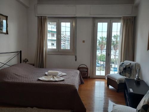 Schlafzimmer mit einem Bett, einem Stuhl und Fenstern in der Unterkunft Pasalimani Long Beach in Piräus