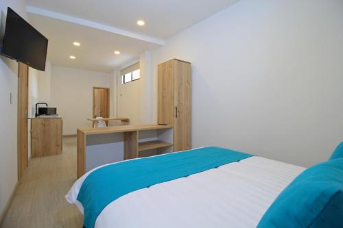 a bedroom with a bed and a desk with a television at Apart Hotel Casa Blanca in Cuenca