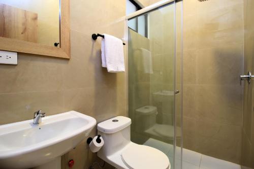 a bathroom with a toilet and a sink and a shower at Apart Hotel Casa Blanca in Cuenca