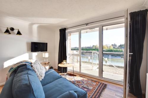 a living room with a blue couch and a large sliding glass door at Nine The Boathouse in Rye