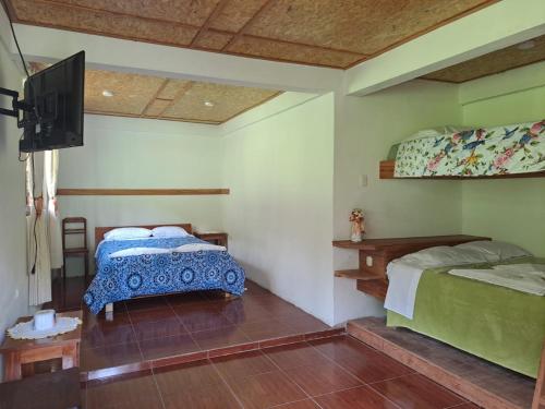 a bedroom with two beds and a flat screen tv at La Ramada de Mama Elena in Oxapampa