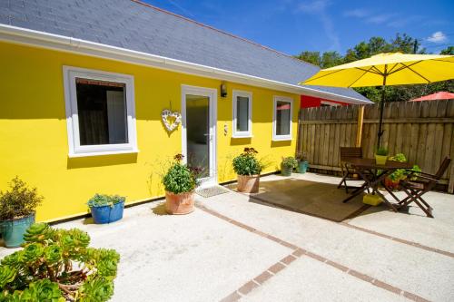 a yellow house with a table and an umbrella at Krissie's in Marazion
