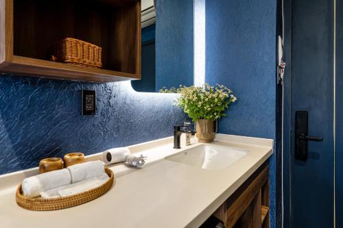 a bathroom with a sink and a blue wall at KunKin Garden Aparthotel in Ho Chi Minh City