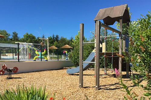 un parc avec une aire de jeux avec un toboggan et des balançoires dans l'établissement Camping Aubigny-Les Clouzeaux, à Aubigny