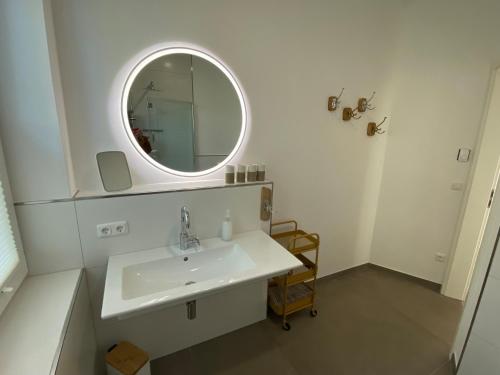 a white bathroom with a sink and a mirror at Flaggschiff Liegeplatz in Dahme