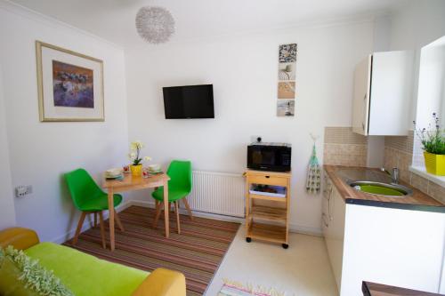 a small kitchen with a table and green chairs at Krissie's in Marazion
