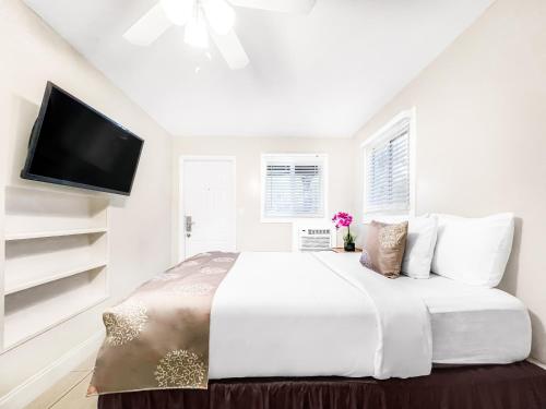 a white bedroom with a large bed and a flat screen tv at The Oasis in Hollywood
