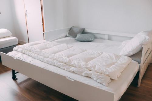 ein Bett mit weißer Bettwäsche und Kissen darauf in der Unterkunft Maison climatisé 2 chambres 700 m de la mer avec parking gratuit in Saint-Cyprien
