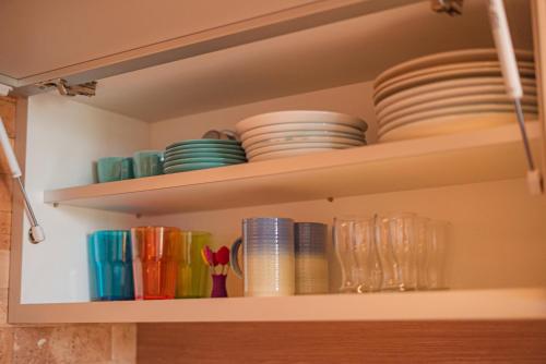 a shelf with plates and bowls and glasses on it at Blue Flat Pedra Azul - Com Vista pra Pedra in Pedra Azul
