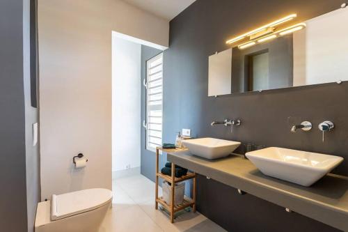 a bathroom with two white sinks and a toilet at Stylish Apartment with Swimming Pool in Kralendijk