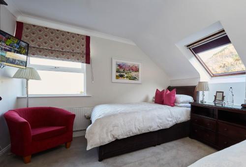 1 dormitorio con 1 cama y 1 silla roja en Luxury Lodges in Doolin Village with Hot Tubs, en Doolin