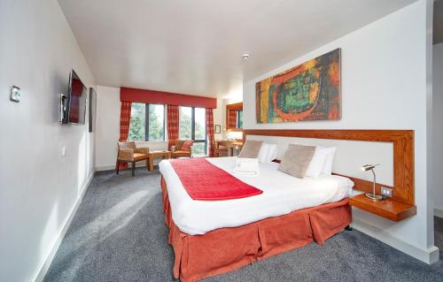 um quarto com uma cama grande e um cobertor vermelho em Lazaat Hotel em Hull