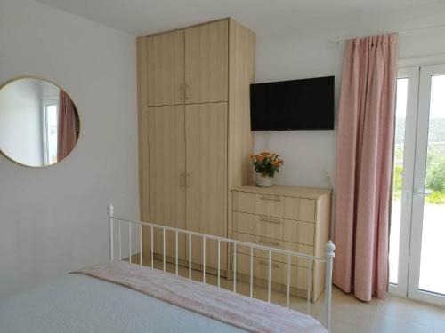 a bedroom with a bed and a cabinet and a mirror at Emmanuela House with garden & sea view - Triopetra in Triopetra