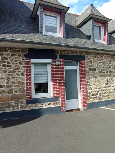 une maison en briques avec deux fenêtres et un garage dans l'établissement Petite maison charmante en baie de Saint-Brieuc entre Paimpol et Erquy Wifi et parking gratuit, à Ploufragan