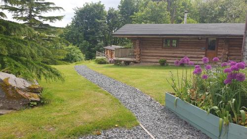 a log cabin with a garden and flowers in front of it at Lake District Log Cabins in Broughton in Furness