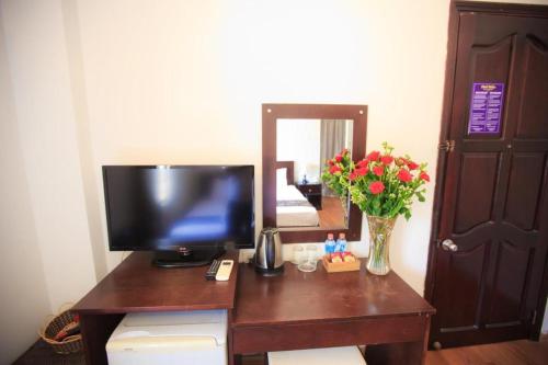 un escritorio con TV y un jarrón de flores en PHỐ BIỂN HOTEL, en Nha Trang