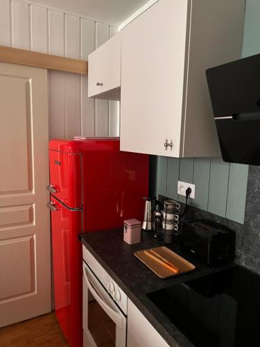 uma cozinha com um frigorífico vermelho e armários brancos em Nid douillet T2 wifi centre historique 3 étoiles em La Rochelle