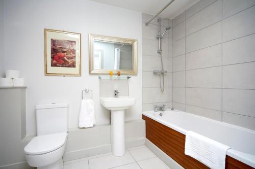 a white bathroom with a sink and a tub and a toilet at Lazaat Hotel in Hull
