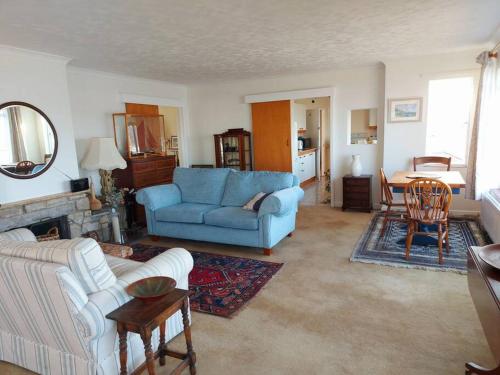 ein Wohnzimmer mit einem blauen Sofa und einem Tisch in der Unterkunft Brooklands Farm Hamble Riverside apartment on the reiver in Southampton